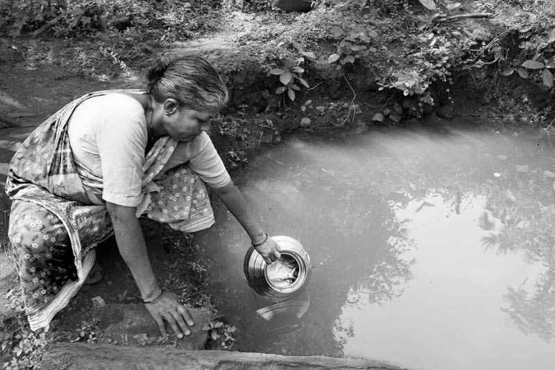 Human Right to Water in Mumbai - A Warli woman taking polluted water from a ditch in the absence of proper water supply